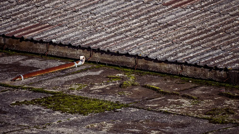 Weathered asbestos-cement roof with visible cracking and moss